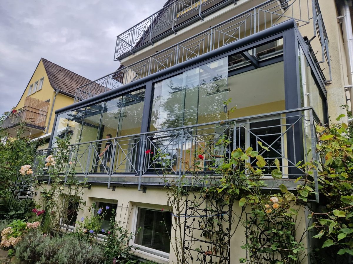 Rahmenlose Glasschiebewände an einer überdachten Terrasse, windgeschützt und transparent