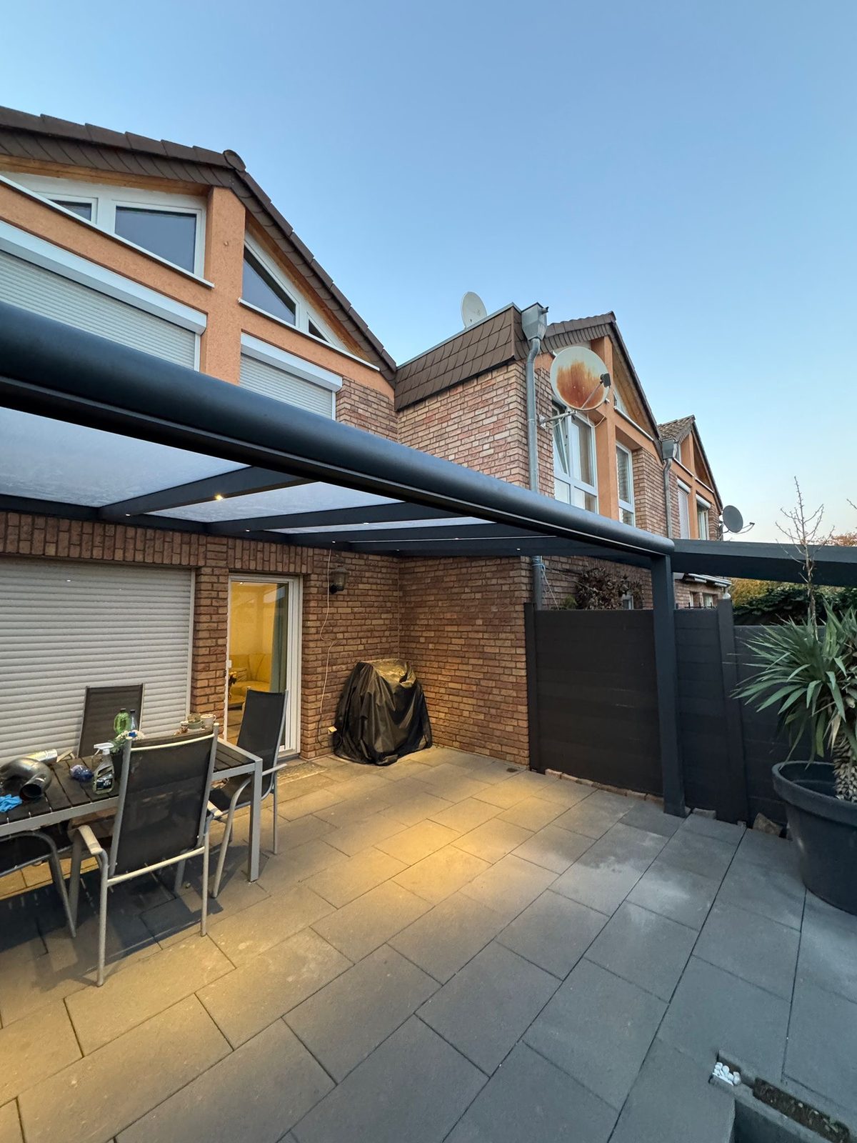 Überdachte Terrasse mit Glasschiebewänden, geöffnet zum Garten