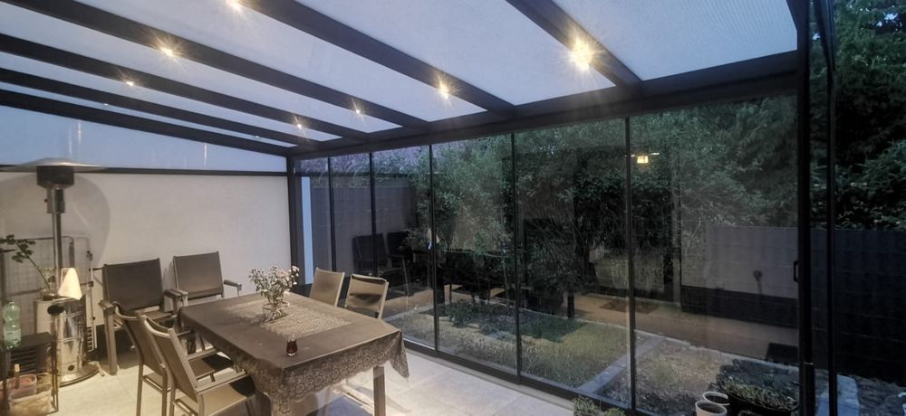 Überdachte Terrasse mit Glasschiebewänden und Wohnbereich