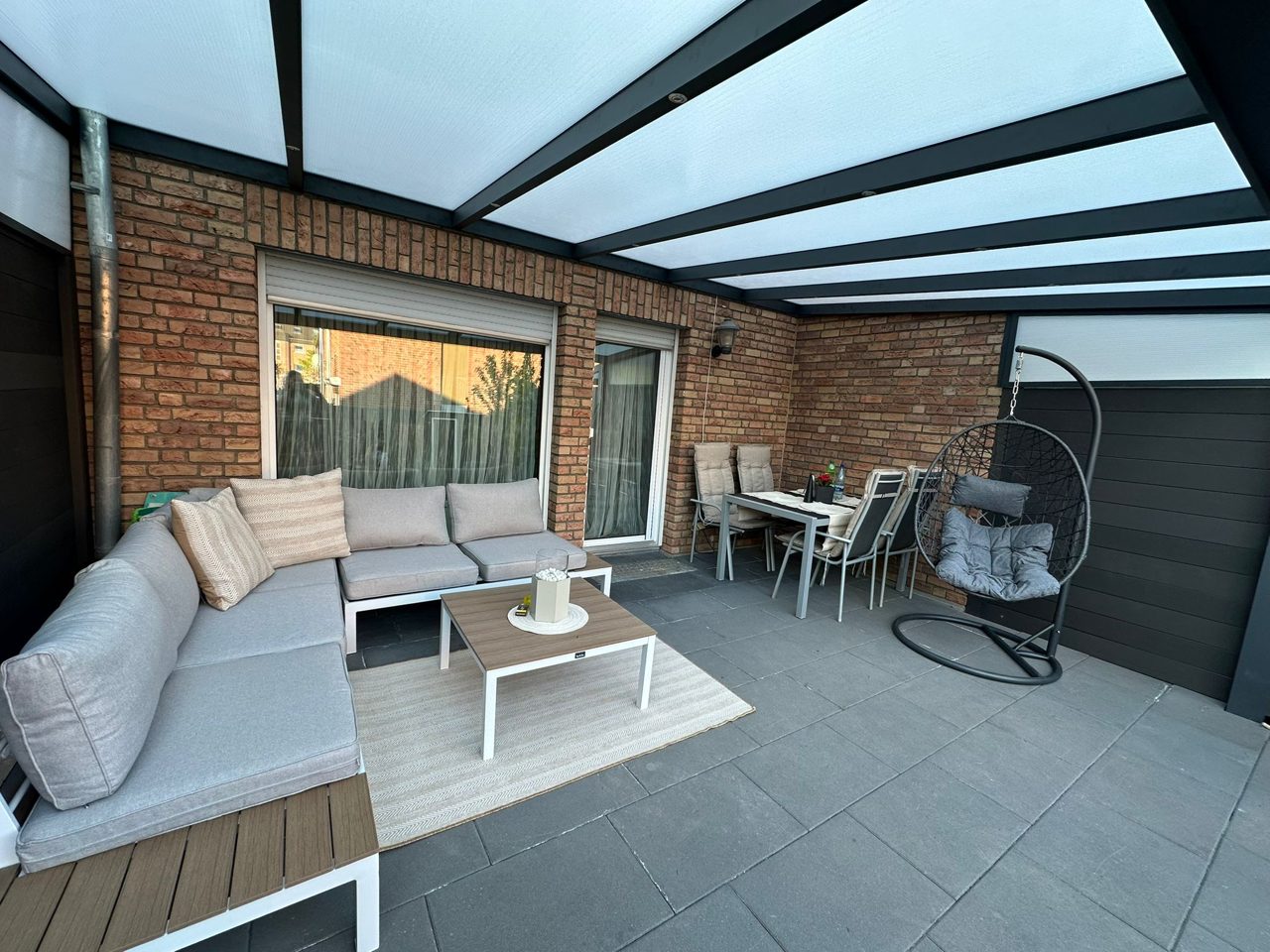 Offene Terrassenüberdachung aus anthrazitfarbenem Aluminium mit Lounge-Ecke