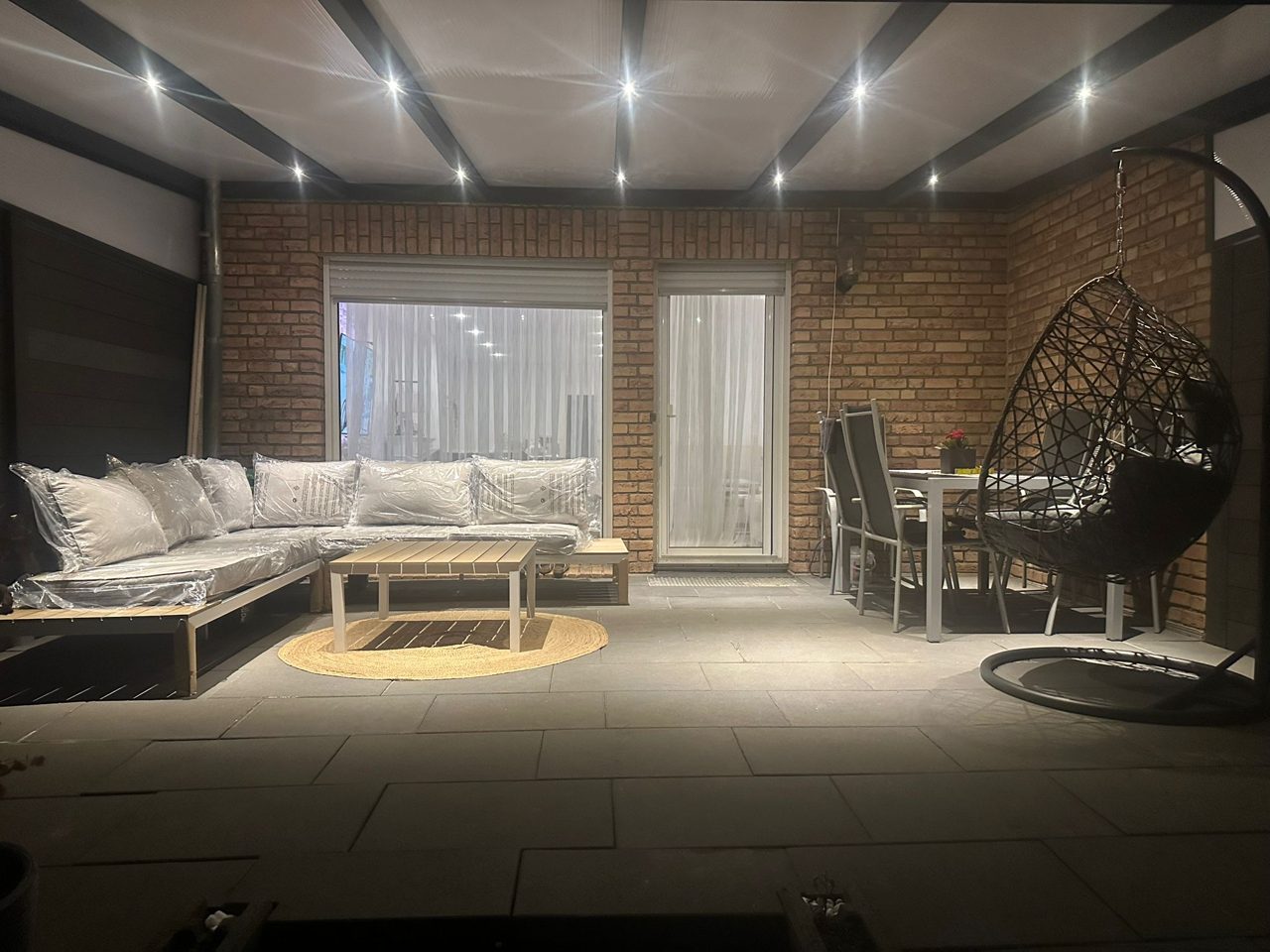 Beleuchtete Terrassenüberdachung mit integrierten LED-Spots bei Abenddämmerung in NRW